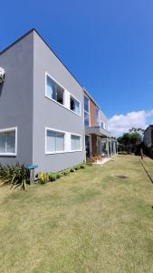 une maison blanche avec une cour devant elle dans l'établissement Rosa Surf Hostel & Food, à Praia do Rosa