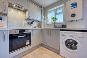 a kitchen with white cabinets and a washer and dryer at Stratton Heights by Apricity Property - 3 bedroom house, great for work or leisure, pet friendly in Cirencester