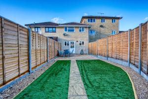 a backyard with a wooden fence and green grass at Stratton Heights by Apricity Property - 3 bedroom house, great for work or leisure, pet friendly in Cirencester