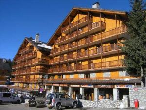 Un gran edificio con coches aparcados delante. en Appartement 2 pièces avec balcon à Méribel, proche commerces et pistes - FR-1-180-86, en Méribel