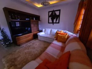 a living room with a white couch and a flat screen tv at Aconchego da Serra in Teresópolis