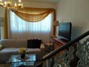 ein Wohnzimmer mit einem Sofa und einem TV in der Unterkunft Condomínio Vila Paradiso in Serra Negra
