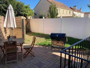eine Terrasse mit einem Tisch, einem Grill und einem Sonnenschirm in der Unterkunft Appartement duplex : Le Cosy in Montgeron