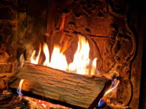 a fire in a stone oven filled with wood at Place Royale pour 10 à 12 personnes à 30 mèt des pistes de Ski et Vtt in Métabief