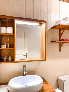 La salle de bains est pourvue d'un lavabo, d'un miroir et de toilettes. dans l'établissement MOOREA - The Golden Reef Bungalow Nuku Hiva, à Temae