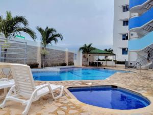 una piscina con una silla blanca y un edificio en Hermoso apto cerca a la playa Bello Horizonte, en Santa Marta