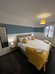 um quarto com uma cama grande com um cobertor amarelo em Erasmus House - 3 Bedrooms - City Centre, Netflix, WIFI, Free Private Parking em Derby