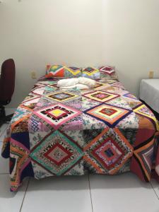a bed with a colorful quilt on top of it at Brisa da Serra Pousada EM SOBRAL-CE in Sobral