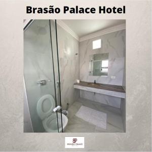 y baño blanco con aseo y ducha. en Brasao Palace Hotel, en Presidente Prudente