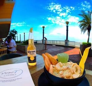 un tazón de camarones y verduras y una botella de cerveza en EcuSuites Vista Río Puerto Santa Ana Wyndham, en Guayaquil