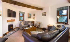 a living room with a leather couch and a fireplace at Drystones in Grasmere