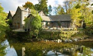 an old stone house with a pond in front of it at Drystones in Grasmere