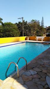 a swimming pool with blue water and a yellow wall at Condomínio Vila Paradiso in Serra Negra