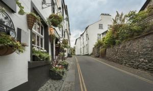 an empty street with buildings and potted plants at Old Village Shop in Ambleside