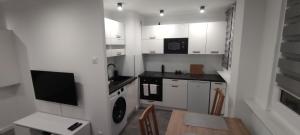 a kitchen with white cabinets and a table with a laptop at Apartament Miedzianka III in Polkowice