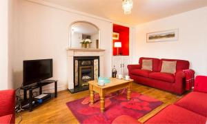 een woonkamer met een rode bank en een open haard bij Biskey Steps in Bowness-on-Windermere