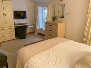 Dormitorio con cama, escritorio y TV en Dove Holme Cottage, en Grasmere