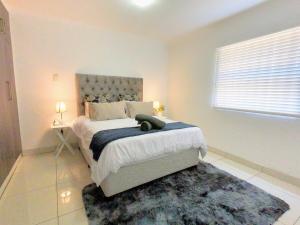 a bedroom with a large bed and a rug at Stunning 2 Bed - Rooftop Braai Area - Sunset Views in Durban