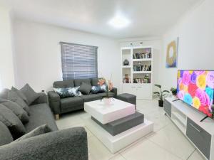 a living room with a couch and a tv at Stunning 2 Bed - Rooftop Braai Area - Sunset Views in Durban