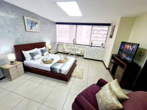 1 dormitorio con cama, sofá y TV en Habitacion Matrimonial Vista Rio junto Wyndham, en Guayaquil