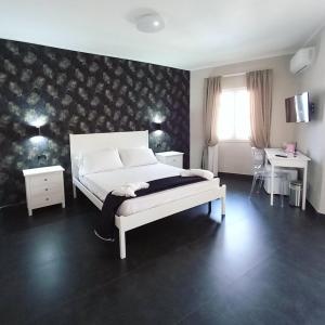 1 Schlafzimmer mit einem weißen Bett, 2 Tischen und einem Fenster in der Unterkunft ALDIVA ROOMS in Torvaianica