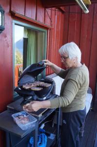 Kobieta gotuje jedzenie w grillu. w obiekcie Rekdal w mieście Vestnes