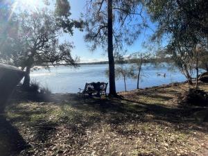 a park bench sitting on the shore of a lake at The downstairs delight 2brm , 6+ guests & dogs ok in Lake Munmorah