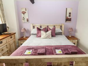 アンブルサイドにあるButtonhole Cottageのベッドルーム1室(紫色のシーツと枕が備わる大型ベッド1台付)