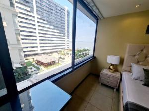 1 dormitorio con cama y ventana grande con vistas en Ecusuites Bellini 404 King RiverView AirportGye, en Guayaquil