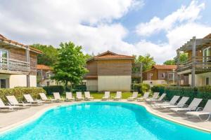a swimming pool with chaises and chairs in a yard at Le Nid in Aureilhan