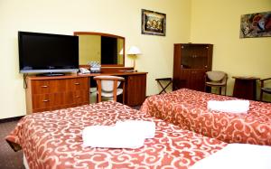 a hotel room with two beds and a flat screen tv at Hotel Wityng in Ślesin