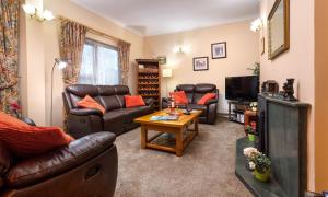 sala de estar con muebles de cuero y TV en Fairhaven en Bowness-on-Windermere