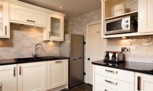 a kitchen with white cabinets and a stainless steel refrigerator at Scafell in Ambleside