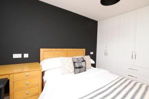a bedroom with a white bed and a black wall at Luxurious double bedroom, ensuite with free Wifi. in Oxford