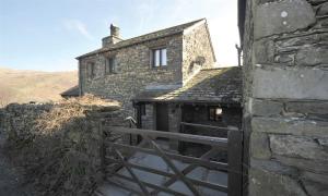una vecchia casa in pietra con un cancello davanti di Butt Hill Cottage a Troutbeck