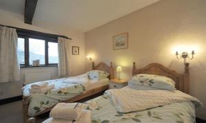 una camera da letto con due letti e una finestra di Butt Hill Cottage a Troutbeck