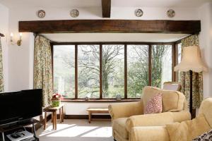un soggiorno con due sedie e una grande finestra di Butt Hill Cottage a Troutbeck Altre 4 foto