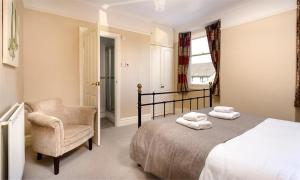 a bedroom with a bed and a chair and a window at Highbank in Bowness-on-Windermere