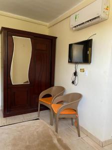 a room with two chairs and a tv on the wall at Khufu Pyramids Hotel in Cairo