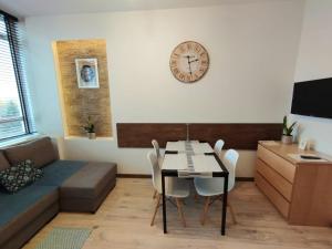 ein Wohnzimmer mit einem Tisch, Stühlen und einer Uhr in der Unterkunft Apartamenty A&B Gold in Kalisz
