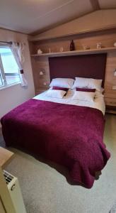 a bedroom with a large bed with a purple blanket at 180 Golden Gate North Wales in Abergele