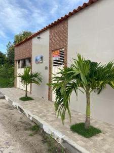 a building with two palm trees in front of it at Cond Praia Linda - Gamboa do Morro de São Paulo in Cairu