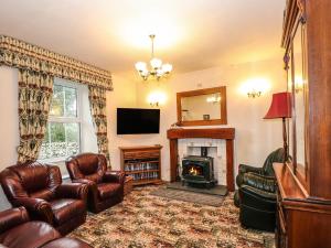 a living room with leather furniture and a fireplace at Raisthwaite Farm in Broughton in Furness