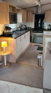 a kitchen with white cabinets and a yellow lamp on a table at 180 Golden Gate North Wales in Abergele