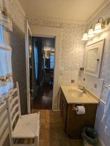 uma casa de banho com um lavatório, um espelho e uma cadeira em English Cottage em Greensboro