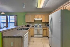 a kitchen with wooden cabinets and a white refrigerator at Cute Pensacola Townhome about 9 Mi to Downtown! in Pensacola