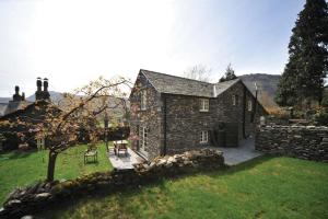 a stone house with a stone wall and a yard at Stone Arthur Cottage in Grasmere