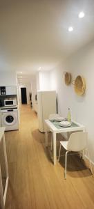 a kitchen with a white table and a white refrigerator at Strada-Beach Las Canteras in Las Palmas de Gran Canaria