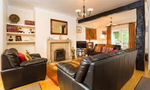 a living room with leather furniture and a fireplace at Priory Lodge in Windermere