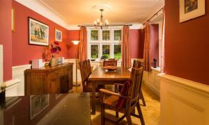 een eetkamer met rode muren en een tafel en stoelen bij Priory Lodge in Windermere